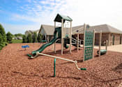 Thumbnail 12 of 15 - a childrens playground with a green swing set at Canterbury apartments in Kalamazoo, MI