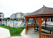 Thumbnail 11 of 31 - Gazebo in front of a pool with apartment buildings in the background at Mosaic Apartments in Avon, Indiana