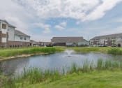Thumbnail 5 of 25 - A pond with a fountain with grove city apartments in the background