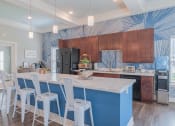 Thumbnail 4 of 25 - Community kitchen with a bar and chairs with dark wood cabinets and black appliances