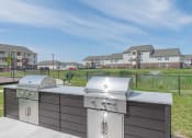 Thumbnail 10 of 25 - Community grill and bbq with a view of the apartments in the background
