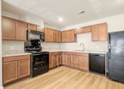 Thumbnail 3 of 50 - A kitchen with wooden cabinets and black appliances.