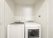 Thumbnail 19 of 50 - A white washing machine and dryer in a small laundry room.