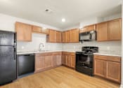 Thumbnail 4 of 50 - A kitchen with wooden cabinets and black appliances.