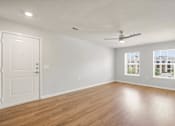 Thumbnail 6 of 50 - A room with a white door, a ceiling fan, and a window showing a building outside.