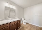 Thumbnail 16 of 50 - A white bathroom with a toilet, sink, and mirror.