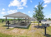 Thumbnail 40 of 50 - A pavilion with picnic tables is surrounded by a grassy area.