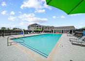 Thumbnail 36 of 50 - A pool with a green umbrella and chairs around it.