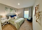 Thumbnail 27 of 34 - A bedroom with a large bed and a blue chair at flats at sundown luxury apartments in north port fl