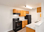 Thumbnail 6 of 14 - A kitchen with black appliances and wooden cabinets.