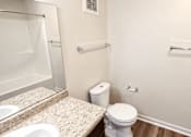 Thumbnail 13 of 19 - A white toilet sits next to a white shower in a bathroom.