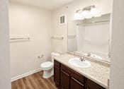 Thumbnail 8 of 19 - A white toilet sits in a bathroom with a sink and mirror.