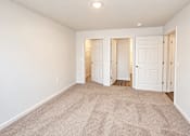 Thumbnail 4 of 19 - A room with carpeted floor and white walls with three doors.