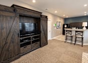 Thumbnail 12 of 19 - A room with a wooden entertainment center and a bar area.