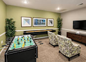 Thumbnail 17 of 19 - A foosball table is in the middle of a room with two chairs and a television.