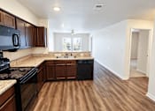 Thumbnail 1 of 19 - A kitchen with dark wood cabinets and a black stove top oven.