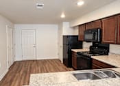 Thumbnail 2 of 19 - A kitchen with a black fridge and microwave.