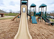 Thumbnail 5 of 19 - A playground with a slide and a green roofed structure.