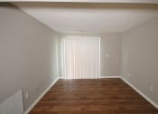 Thumbnail 7 of 17 - Empty living room with a hardwood floor and a door with blinds closed