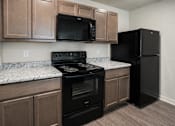 Thumbnail 2 of 21 - A kitchen with black appliances and brown cabinets.
