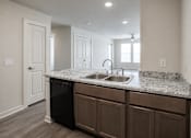 Thumbnail 8 of 21 - A kitchen with a black dishwasher and brown cabinets.