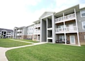 Thumbnail 11 of 20 - Apartment complex with a green lawn in front.