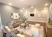 Thumbnail 19 of 20 - A living room with a grey couch, a coffee table, and a television.