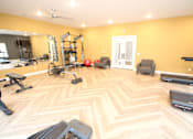 Thumbnail 14 of 20 - A spacious room with a wooden floor and a variety of exercise equipment.