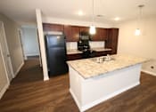 Thumbnail 2 of 20 - A kitchen with a black fridge and wooden cabinets.