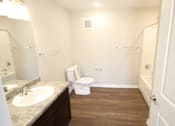 Thumbnail 8 of 20 - A white toilet sits in a bathroom with a sink and mirror.