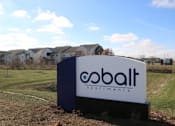 Thumbnail 2 of 25 - A Cobalt Apartments sign is in front of a grassy area with houses in the background.
