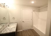 Thumbnail 19 of 25 - A bathroom with a sink, mirror, and shower.