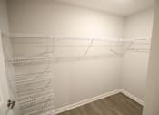 Thumbnail 20 of 25 - A white closet with a wooden floor and shelves.