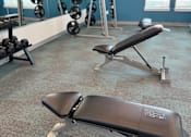 Thumbnail 75 of 83 - A gym with a bench, weights, and a mirror.