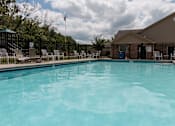 Thumbnail 4 of 24 - A swimming pool surrounded by lounge chairs and a fence.