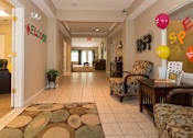 Thumbnail 16 of 24 - A hallway with a welcome sign and a chair with a pillow on it.