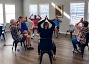 Thumbnail 51 of 58 - a group of people sitting in a circle in a class room with their hands up