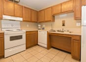 Thumbnail 12 of 24 - A kitchen with wooden cabinets and white appliances.