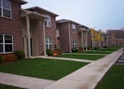 Thumbnail 5 of 6 - Apartment building with a walkway in front.
