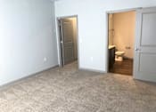 Thumbnail 26 of 31 - Empty bedroom with a bathroom in the background at Mosaic Apartments in Avon, Indiana