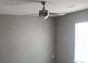 Thumbnail 6 of 7 - A room with a ceiling fan and a window.
