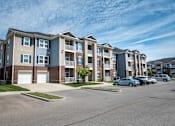 Thumbnail 13 of 31 - Row of apartment buildings with cars parked in front of them at Mosaic Apartments in Avon, Indiana