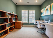 Thumbnail 8 of 31 - Small room with a book shelf and a long desk with computer monitors and chairs with 2 windows at Mosaic Apartments in Avon, Indiana