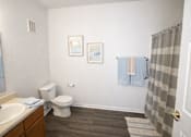 Thumbnail 4 of 16 - A bathroom with a toilet, sink, and shower curtain.