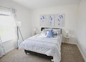 Thumbnail 2 of 16 - A bedroom with a bed, two lamps, and a painting on the wall.
