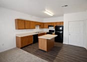 Thumbnail 1 of 16 - A kitchen with wooden cabinets and a black fridge.