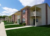 Thumbnail 2 of 13 - Apartment building with a green lawn in front.