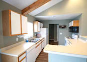 Thumbnail 4 of 13 - A kitchen with wooden cabinets and a white counter.