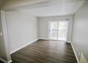Thumbnail 7 of 13 - A living room with wooden floors and a sliding glass door at paragon pointe apartments in frankfort indiana