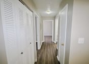 Thumbnail 8 of 13 - A hallway with white doors and wood floors.